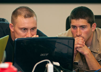 Photo of two 2012 CDX participants concentrating behind a computer monitor.